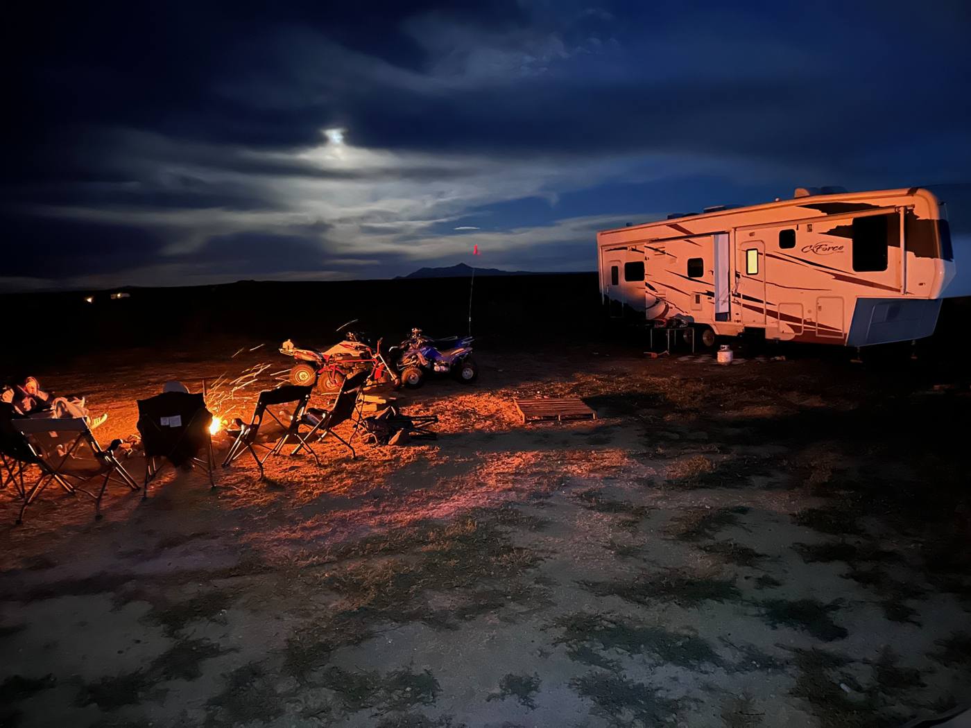 RV and campfire under a moonlit desert sky